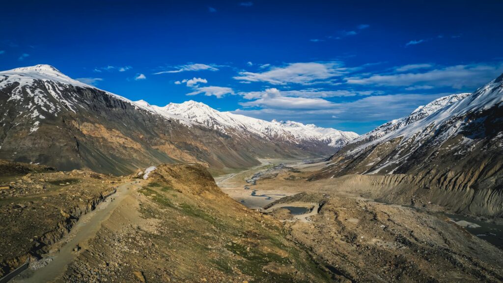 A panoramic view of Zanskar Valley in Himachal Pradesh, showcasing rugged Himalayan mountains, winding rivers, and remote villages.